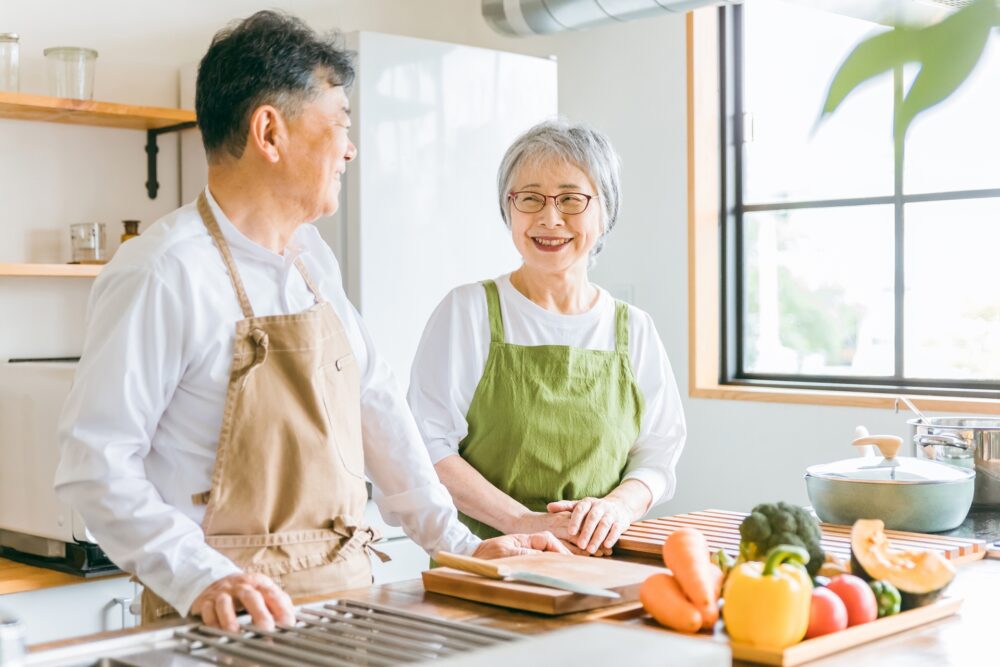 60代の夫婦が台所で向かい合って微笑んでいる写真