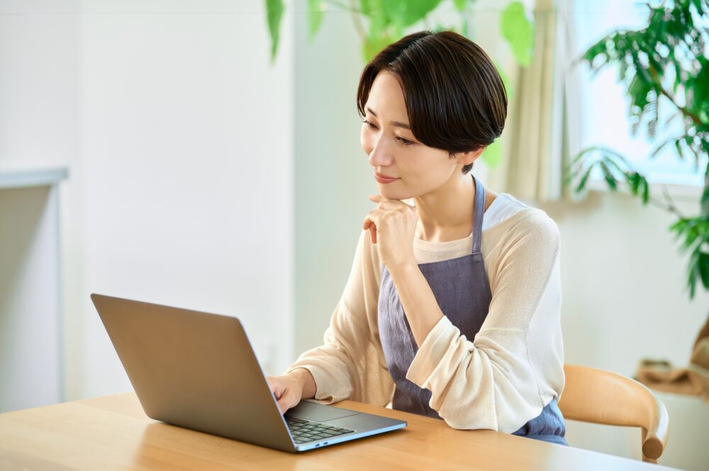 パソコンを見ながら考えている女性の写真