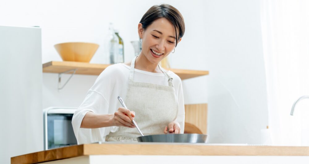 料理のボウルの中身を和えている女性。