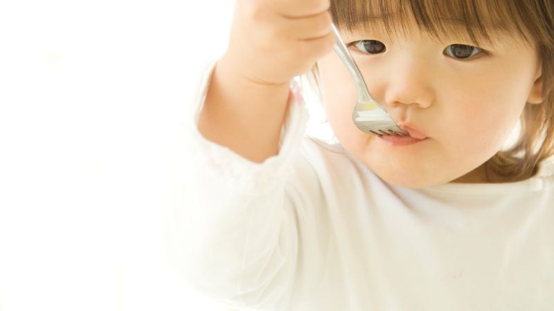 フォークを使って食事をしている子どもの写真