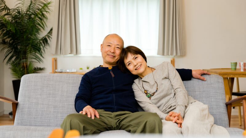 ソファでくつろぐ中年の夫婦の写真