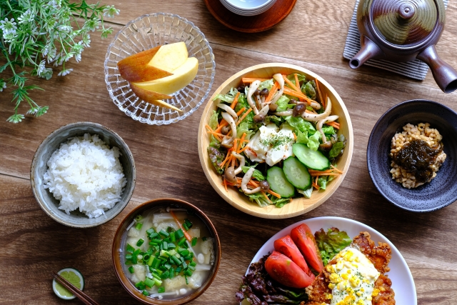 白いご飯、お味噌汁、野菜サラダ、納豆、チキンステーキ、リンゴの献立写真